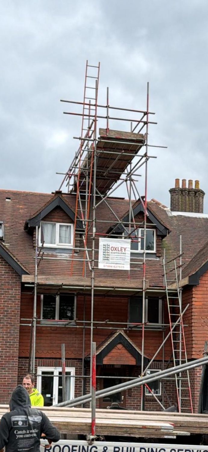 Tower scaffold and crew on a house with Oxley banner
